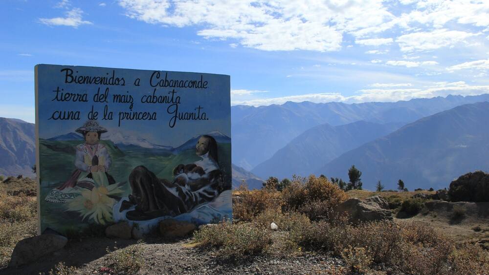 A sign with a painting of a woman and a child, and mountains in the background.