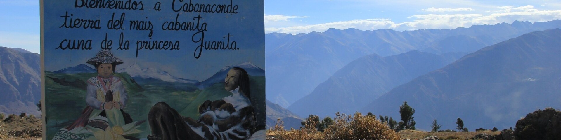 Um letreiro com uma pintura de uma mulher e uma criança, e montanhas ao fundo.