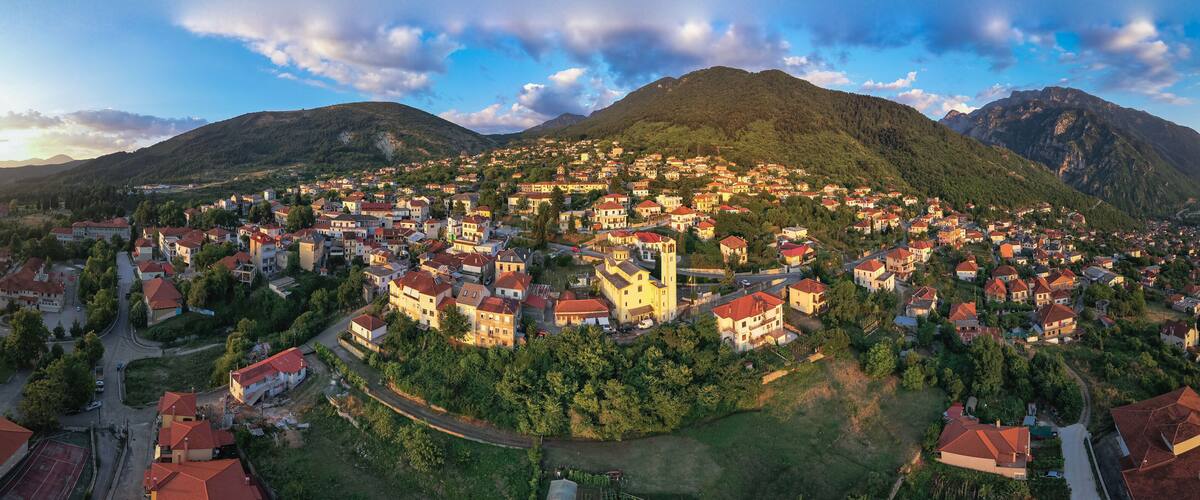A town nestled in a valley with a prominent church and mountains in the background.