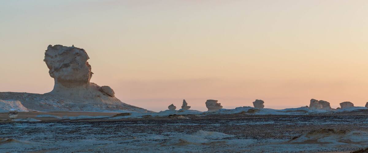 A desert landscape with prominent rock formations during sunset.