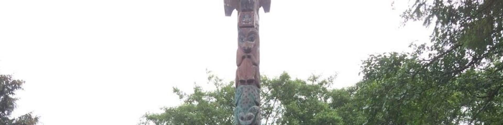 A totem pole with a painted mural on a wooden structure.
