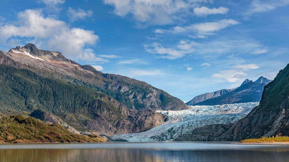 A glacier in a mountainous valley with a clear sky.