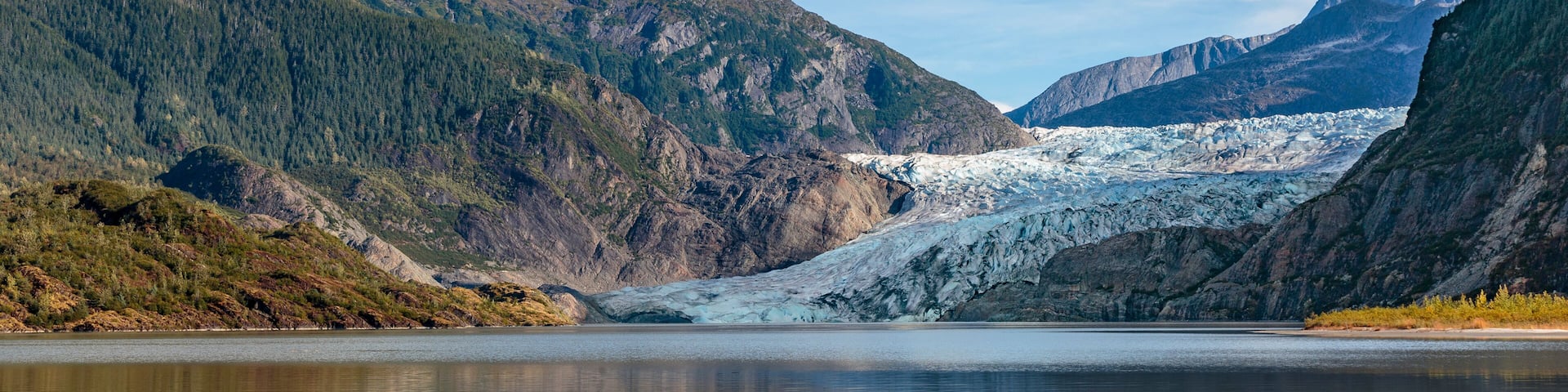 A glacier in a mountainous valley with a clear sky.