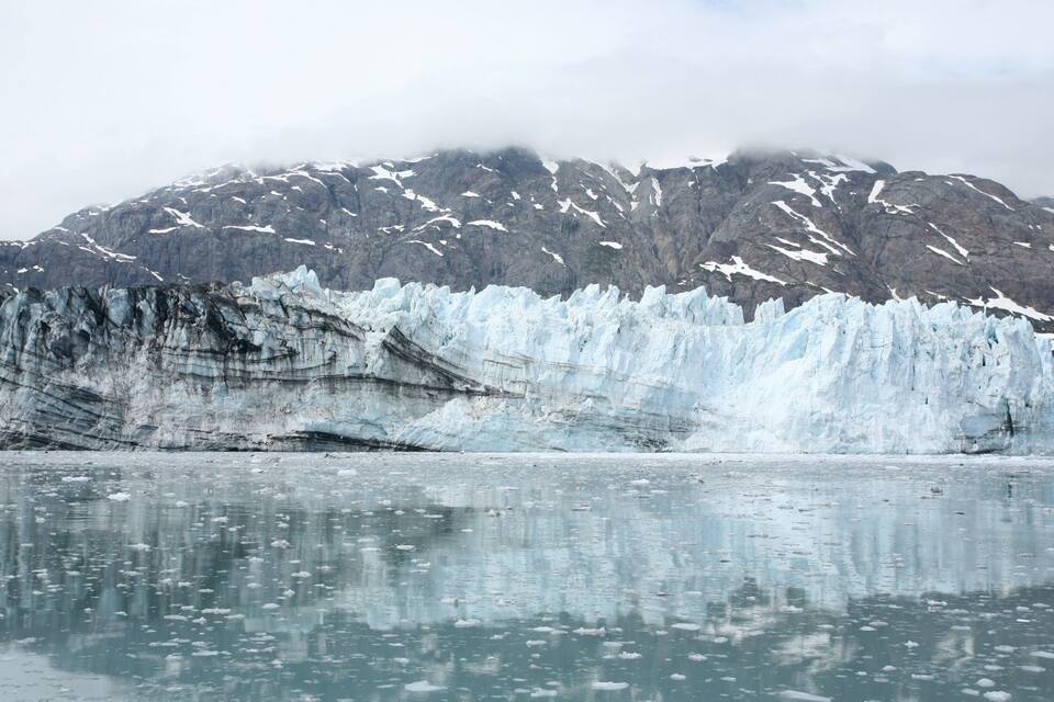 A glacier with a rocky mountain in the background.