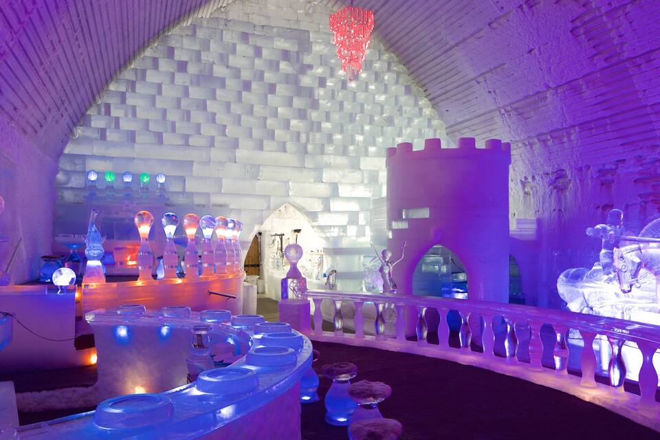 An ice hotel interior with ice sculptures and a castle-like structure.