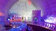 An ice hotel interior with ice sculptures and a castle-like structure.