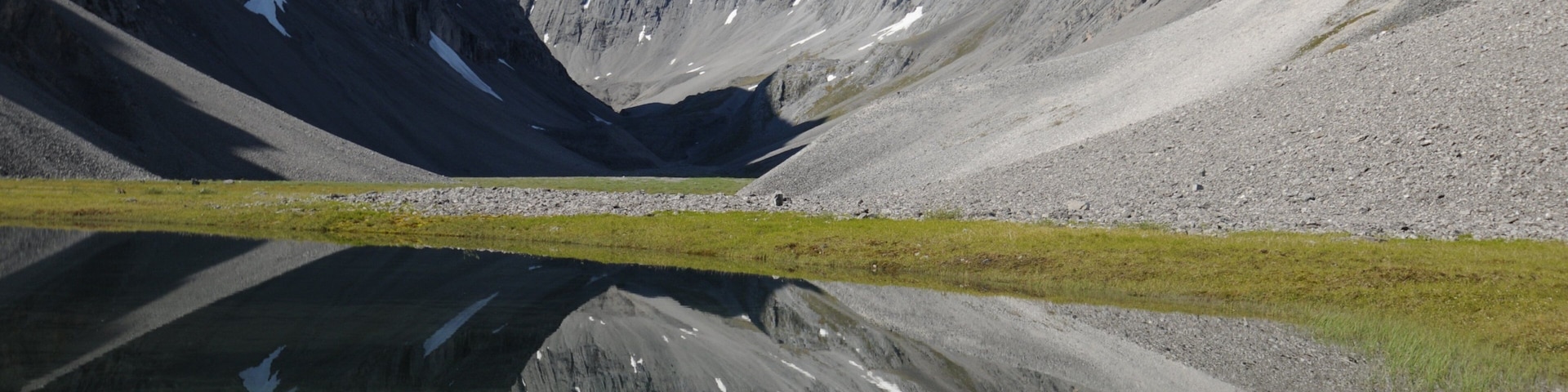 Eine Berglandschaft mit einem See, der die Berggipfel spiegelt.
