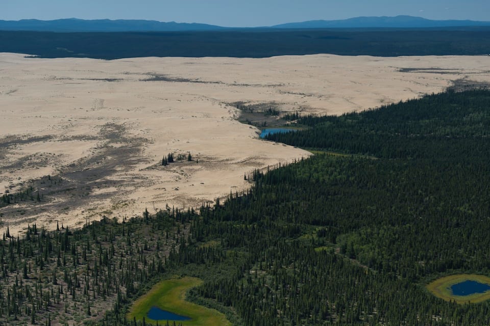 A vast desert landscape with sparse vegetation and a small lake.