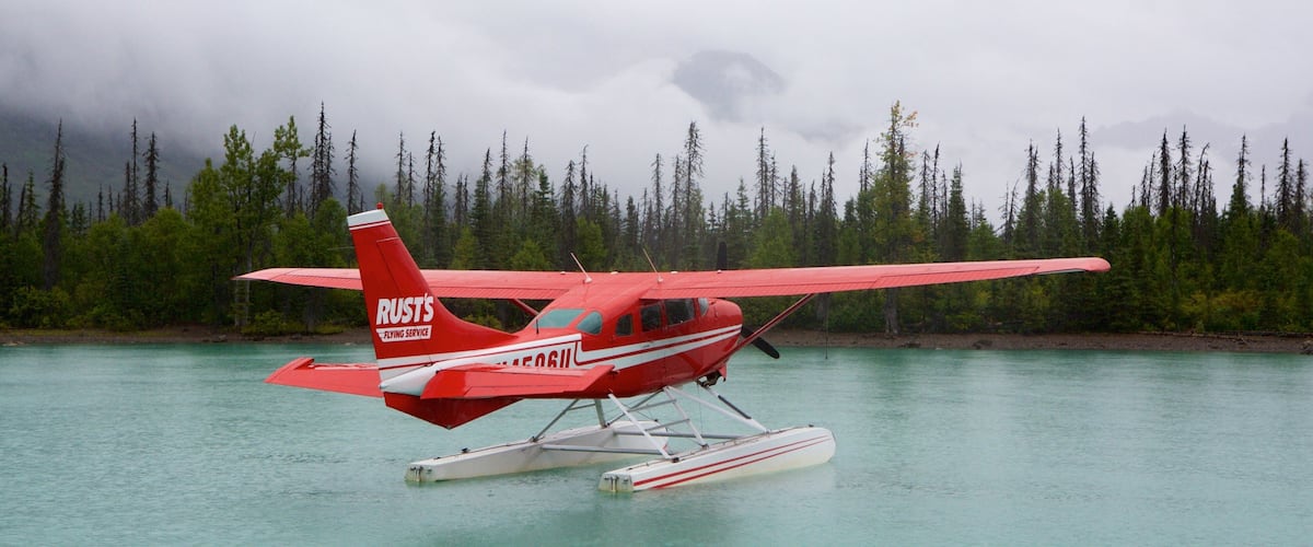 A red seaplane with the registration number N5G61 on water.