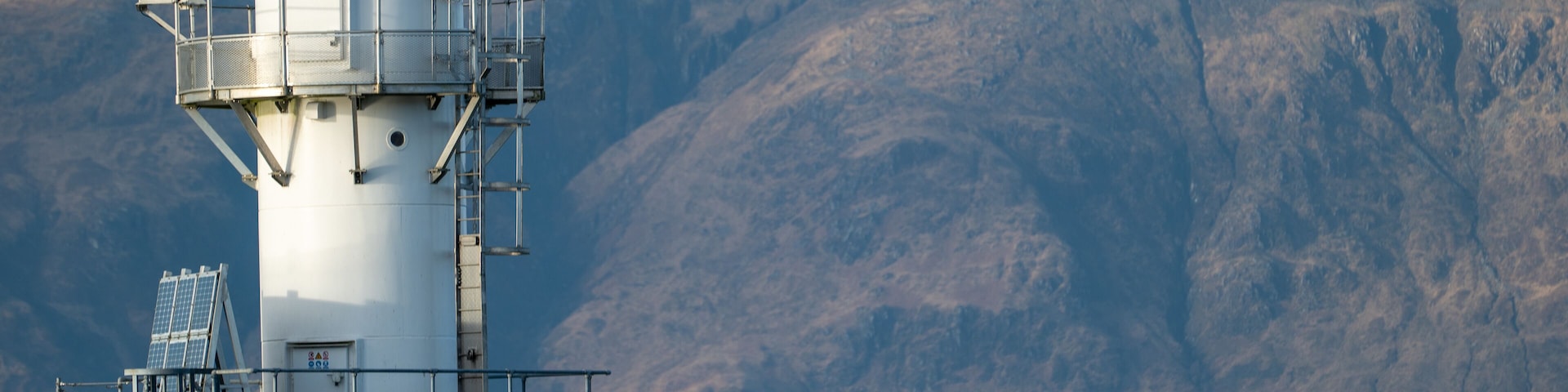 Sentinel of the Sea: Port Appin Coastal Lighthouse Against Mountain Backdrop