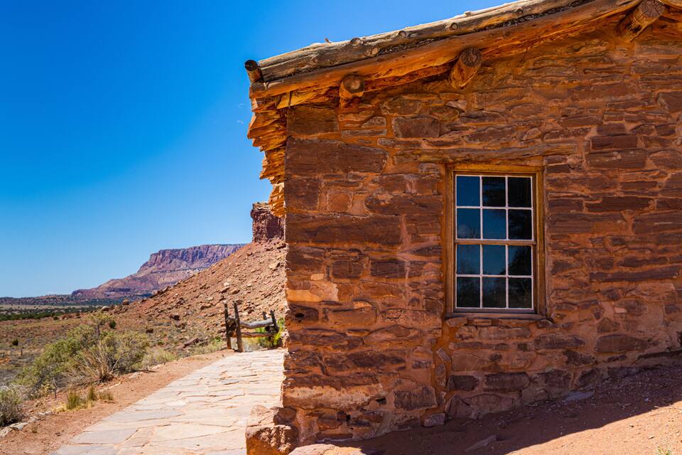 Un edificio de piedra con una ventana y un camino de piedra que lo conduce.