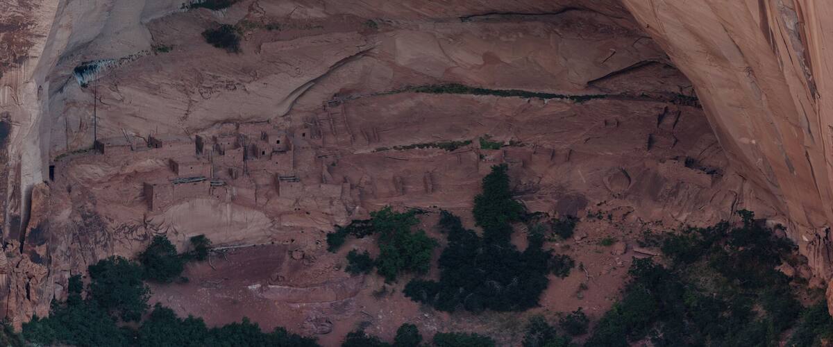 A large rock formation with an arch and layered sedimentary rock.
