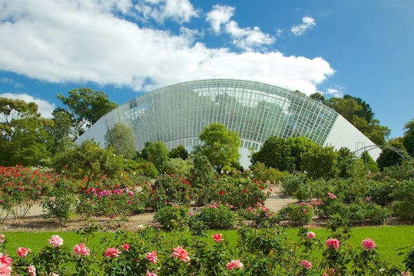 A large glass greenhouse surrounded by lush gardens and trees.