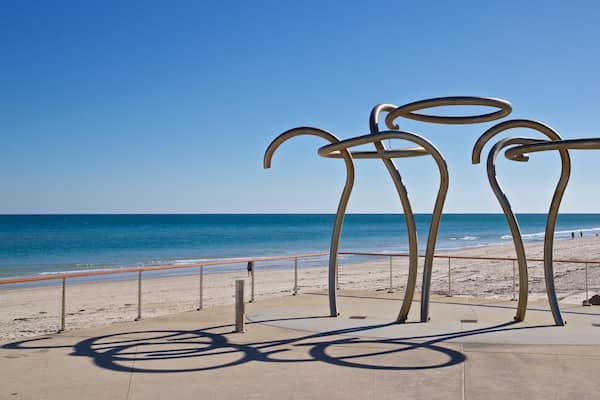 Une plage parsemée de sculptures métalliques, sous un ciel d’un bleu limpide.