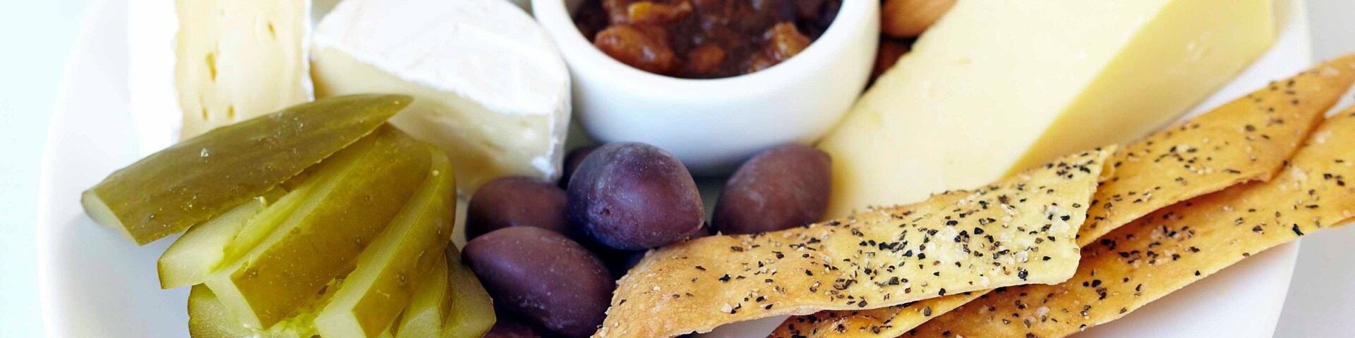 Una tabla de quesos y embutidos con escabechados y frutos secos.