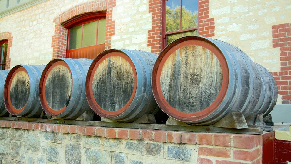 A row of old wooden barrels stacked against a brick wall.