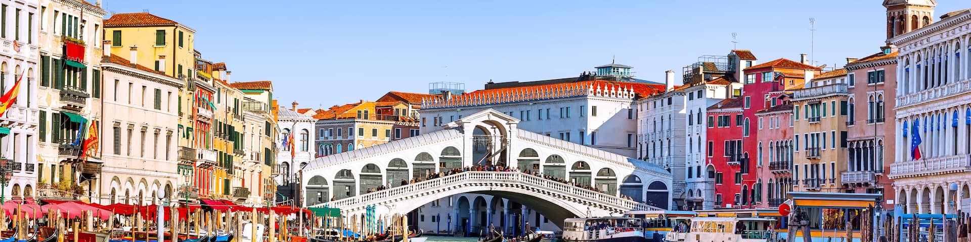 Panoramic view of Grand Canal with Rialto Bridge and gondoliers in Venice, Italy. Panorama of Rialto Bridge and gondola on the Grand Canal in Venice, Italy.