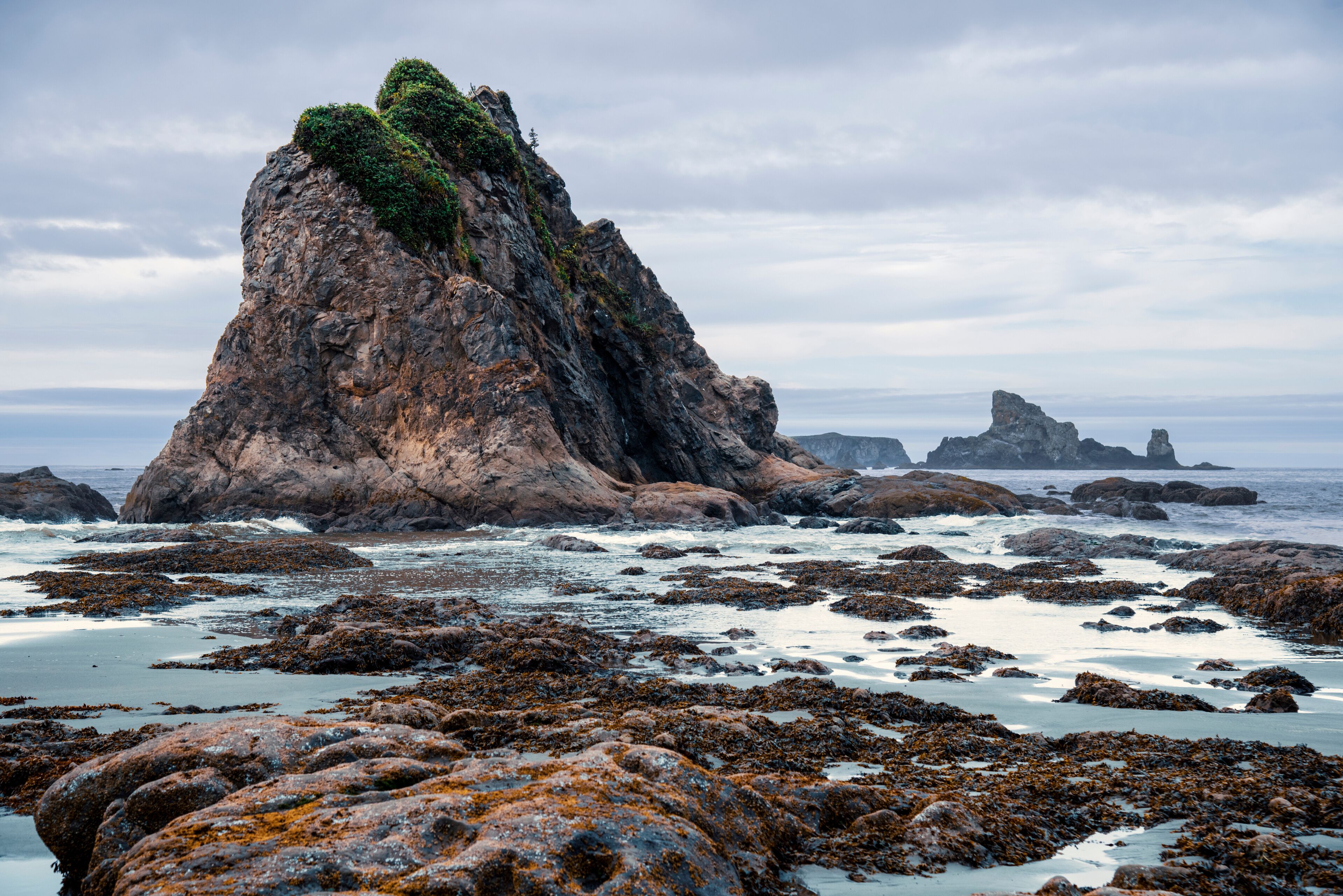 Haystack rock formations on a Pacific Northwest beach, mid day overcast cloudy sky.