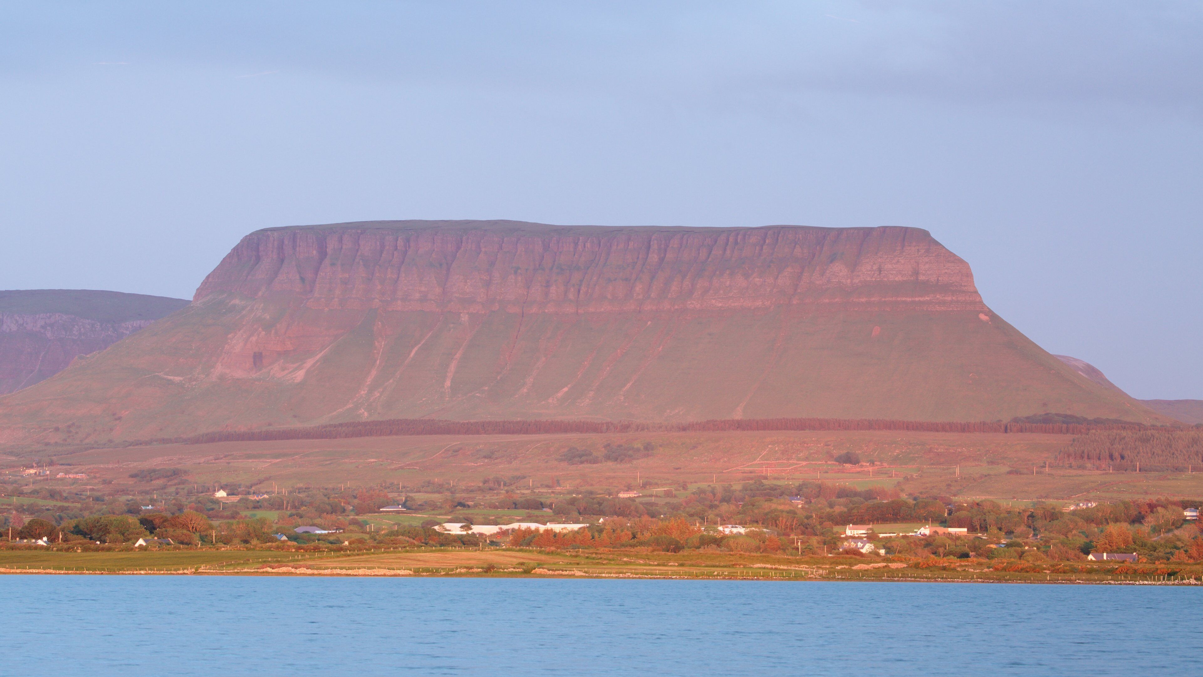 A large plateau with a flat top, surrounded by forested hills.