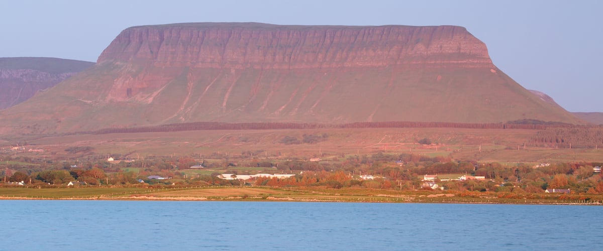A large plateau with a flat top, surrounded by forested hills.