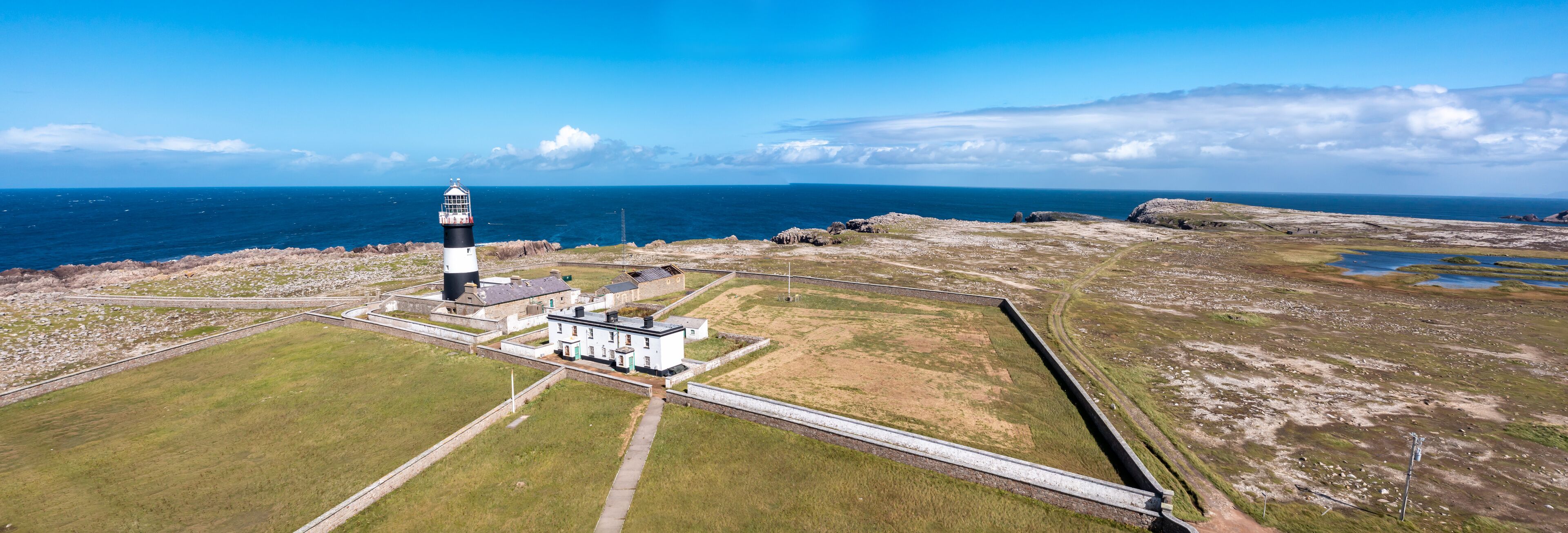 A lighthouse on a rocky coastline with a clear sky.