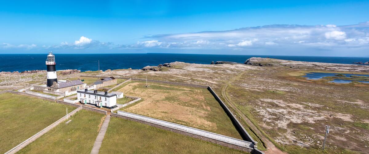 A lighthouse on a rocky coastline with a clear sky.