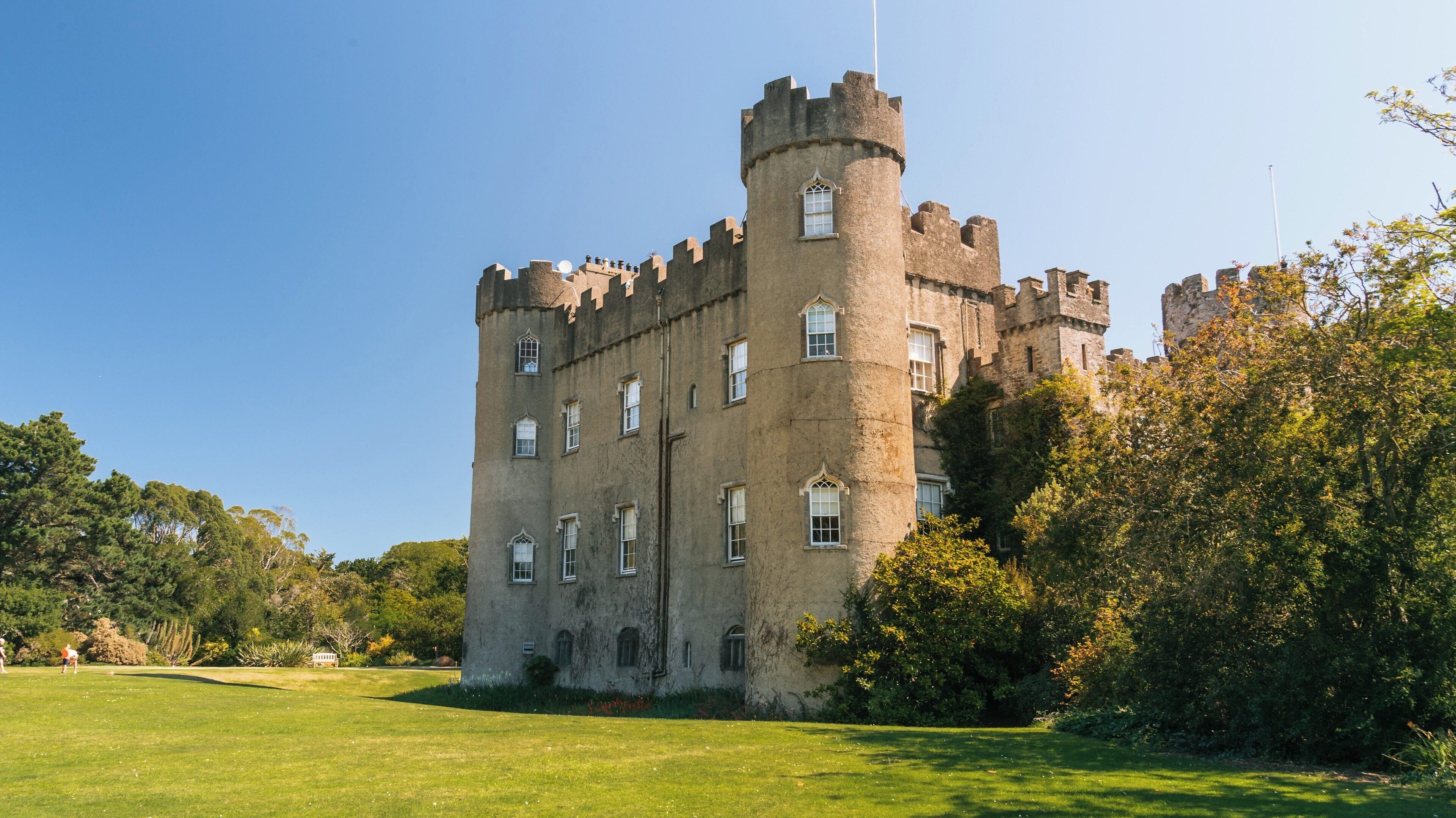 Malahide Castle surrounded by lush greenery on a bright sunny day in Malahide, Ireland