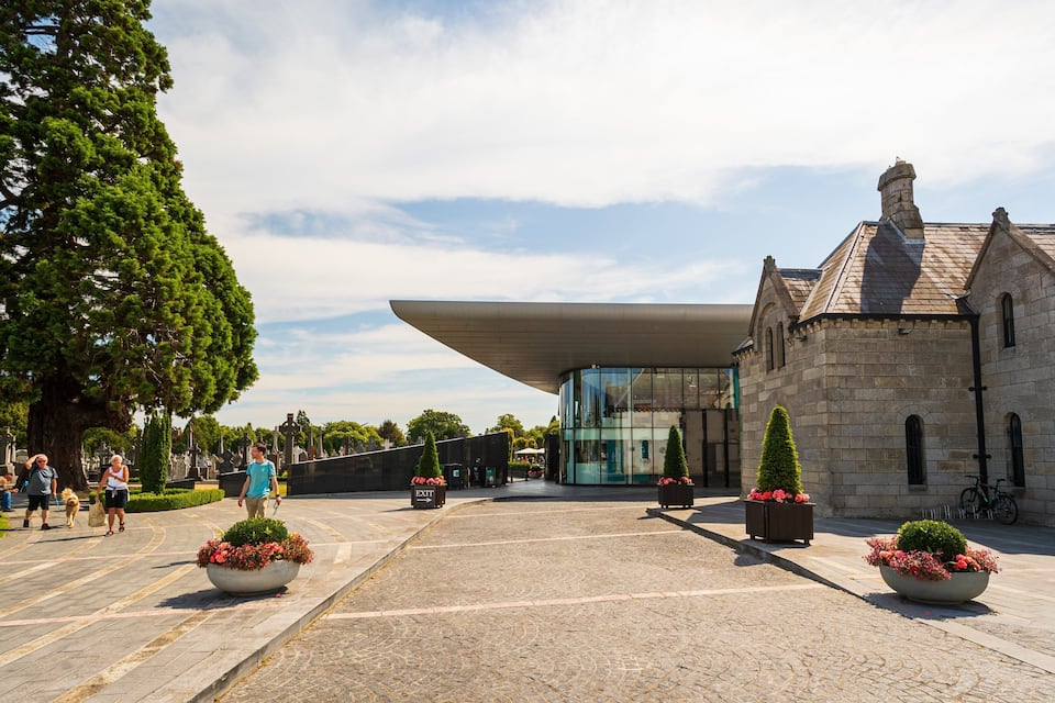 A cemetery with a modern building and stone structures.
