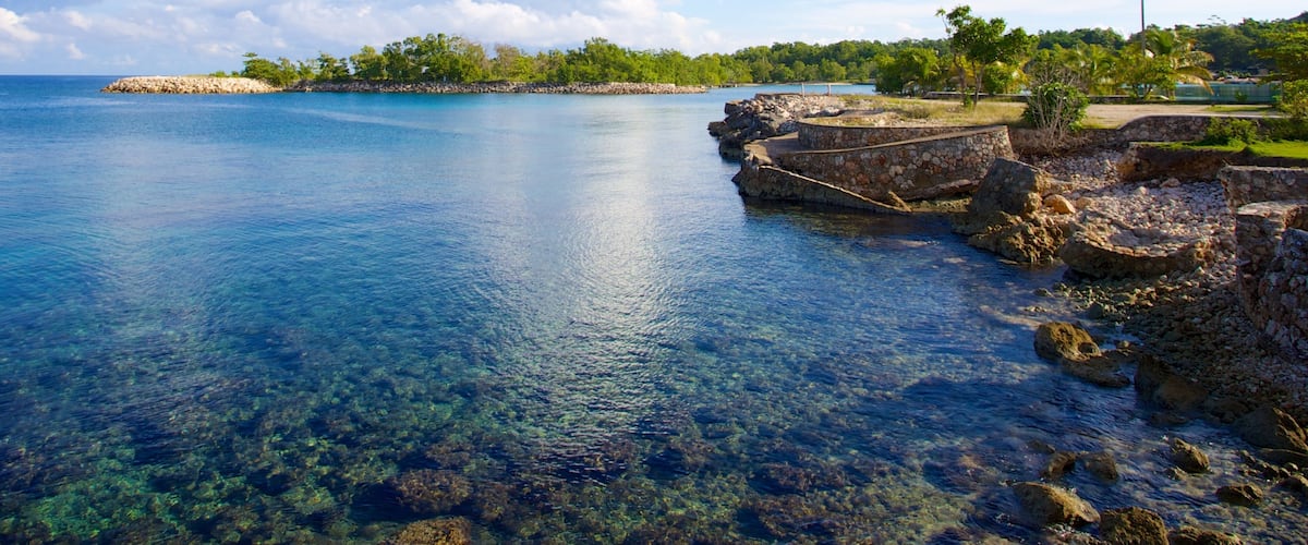 A coastal landscape with clear blue water, rocky shorelines, and a distant island.