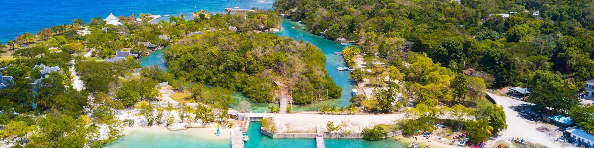 Une île tropicale aux eaux turquoise et limpides, avec un quai et une variété de bateaux.