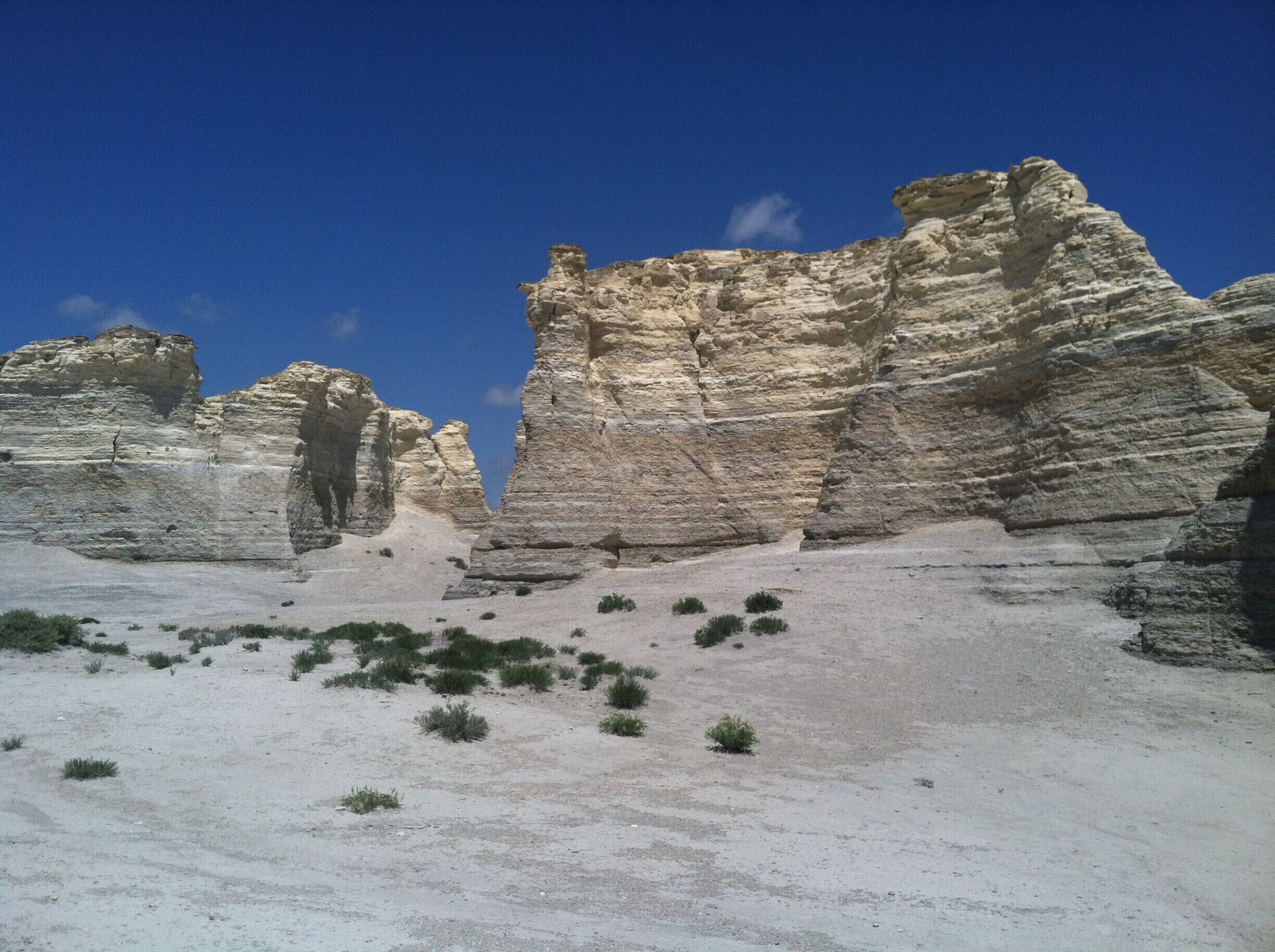 A desert landscape with layered rock formations and sparse vegetation.