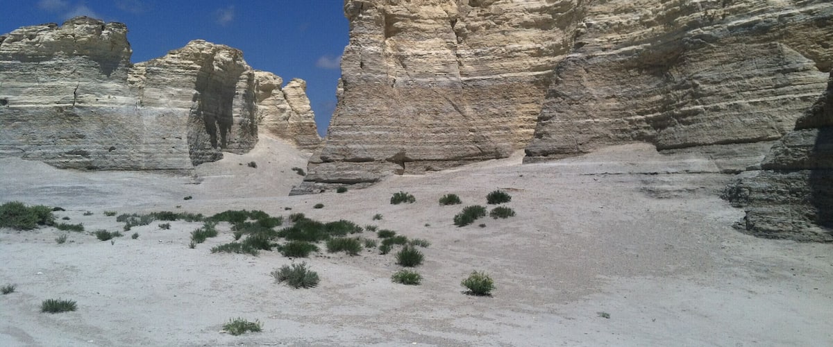 A desert landscape with layered rock formations and sparse vegetation.