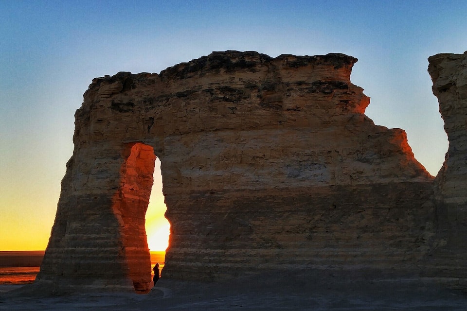 A rock formation with a natural arch at sunset.