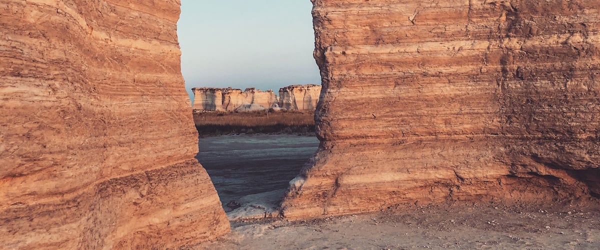 A natural rock formation with a clear blue sky visible through a narrow opening.
