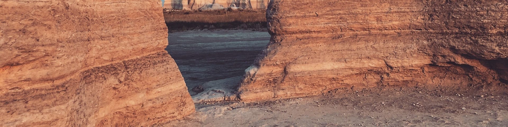 A natural rock formation with a clear blue sky visible through a narrow opening.