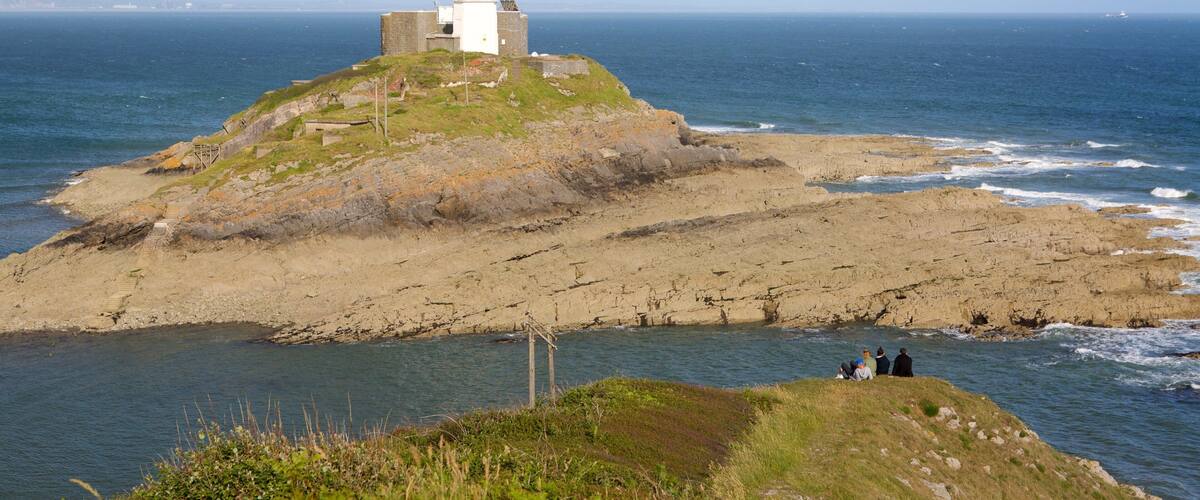 A white lighthouse on a rocky island with a sea view.