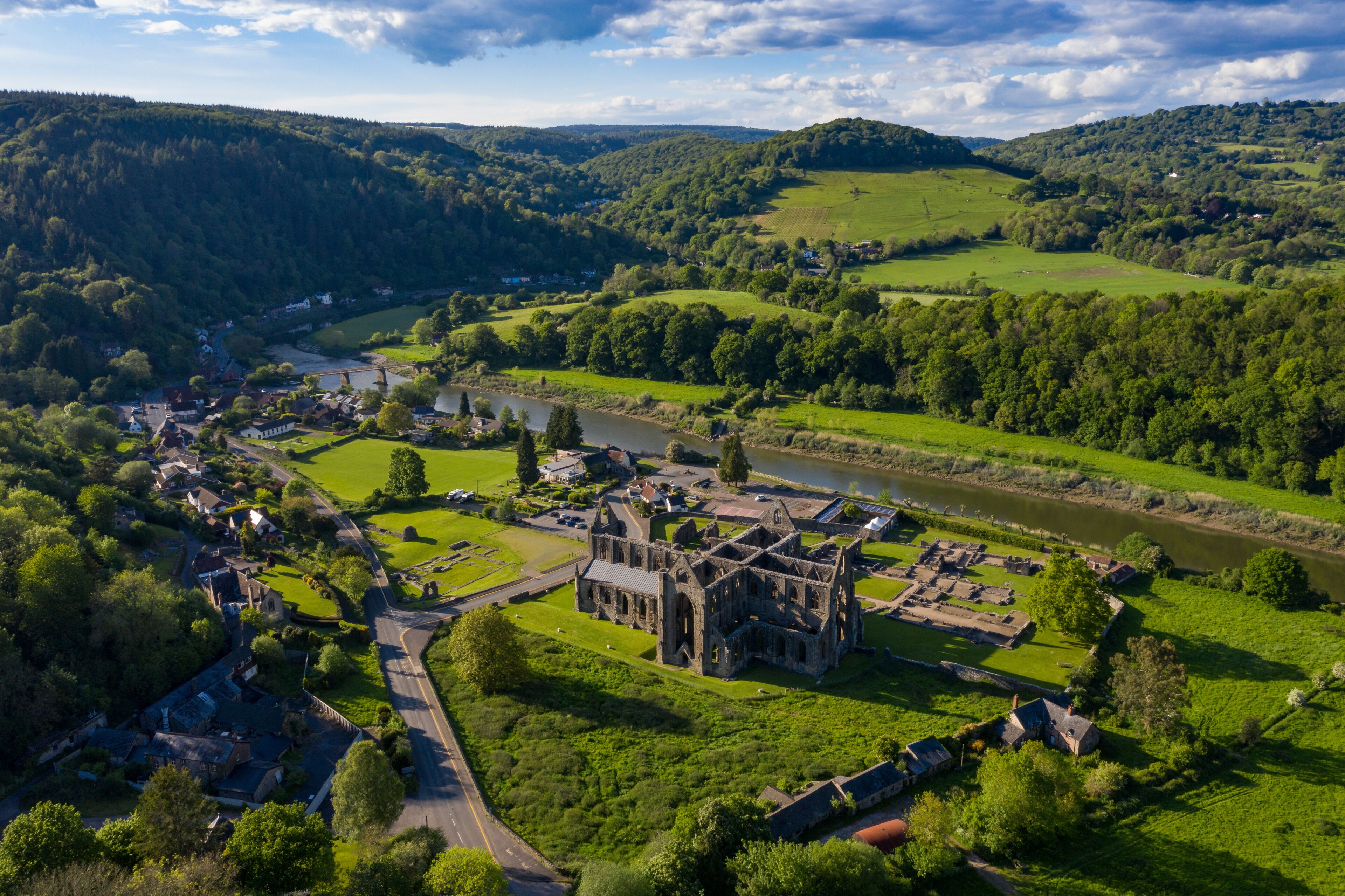 An aerial view of a historic castle surrounded by lush green fields and a river.