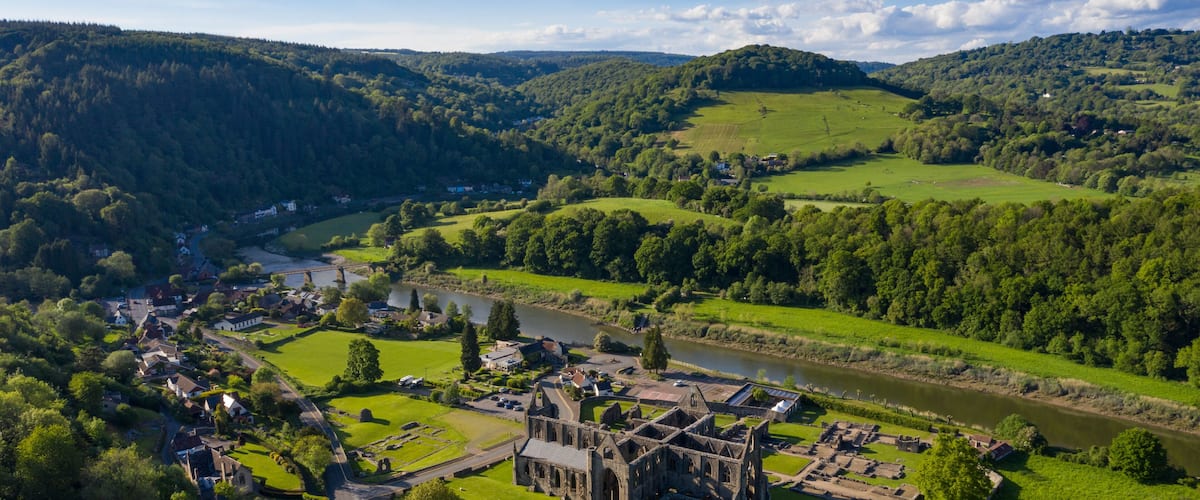 An aerial view of a historic castle surrounded by lush green fields and a river.