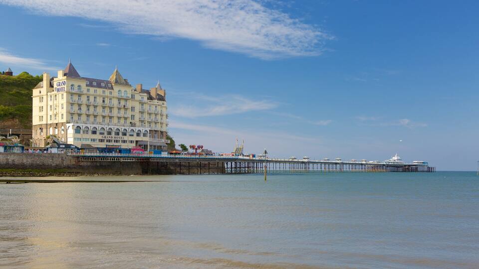 A coastal scene with a large hotel, a pier extending into the sea, and calm waters.