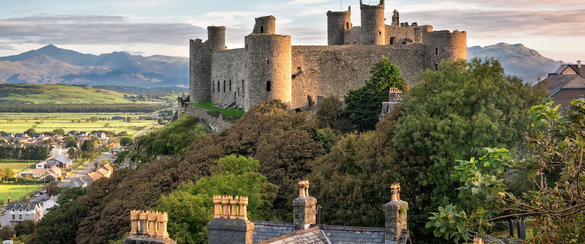 A historic castle on a hill, surrounded by lush greenery and a village below.