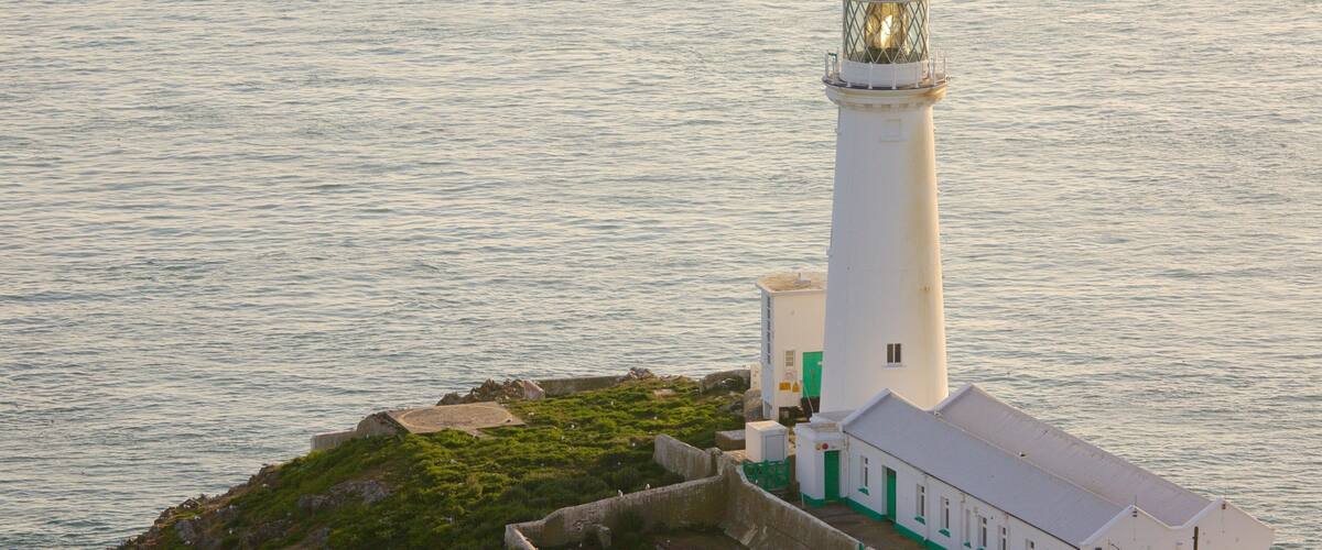 A lighthouse on a small island with a clear view of the surrounding water.