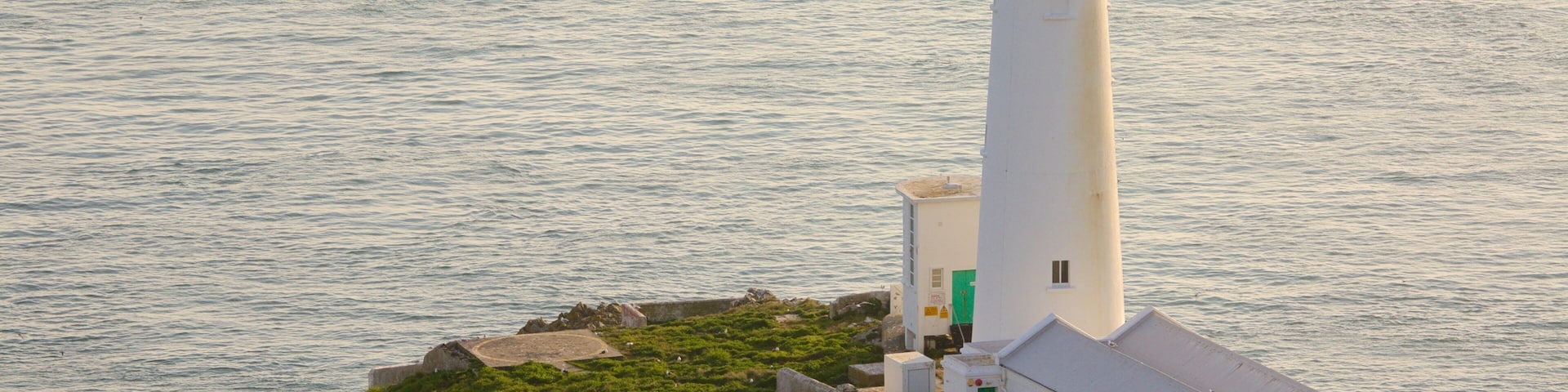 A lighthouse on a small island with a clear view of the surrounding water.