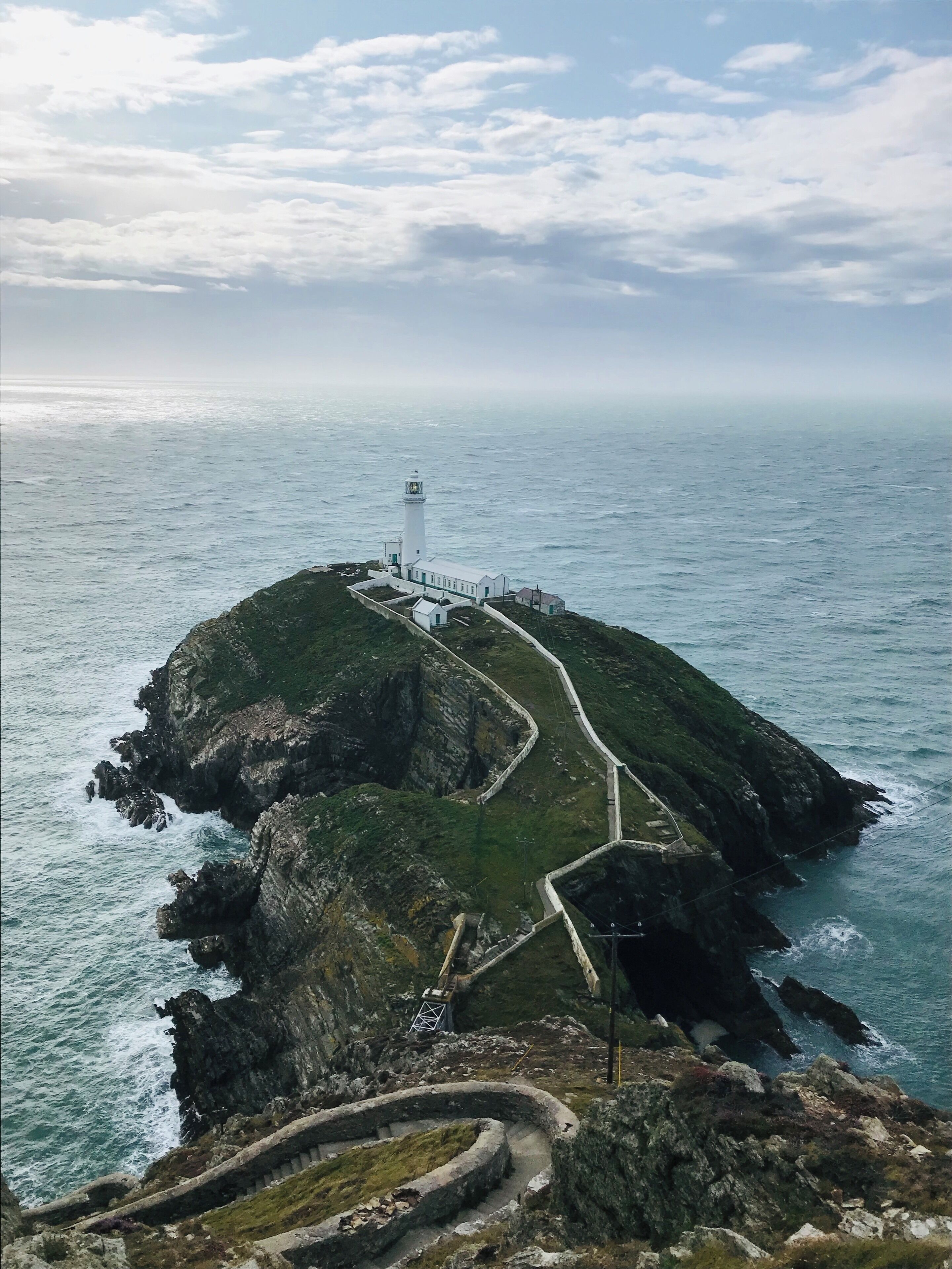 A lighthouse on a rocky island surrounded by the ocean.