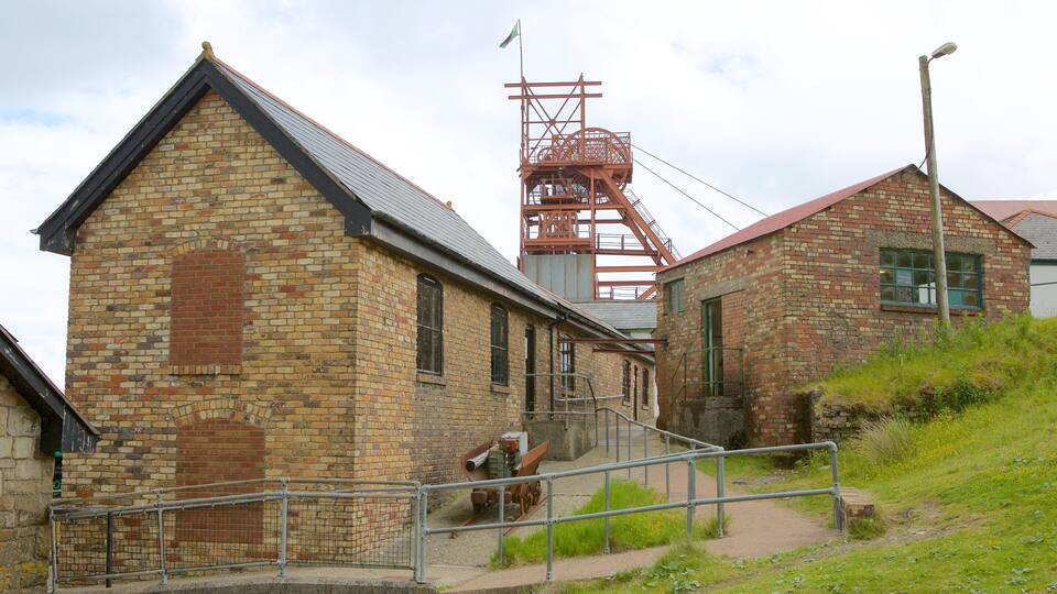 An old brick building with a metal staircase and a red metal structure in the background.