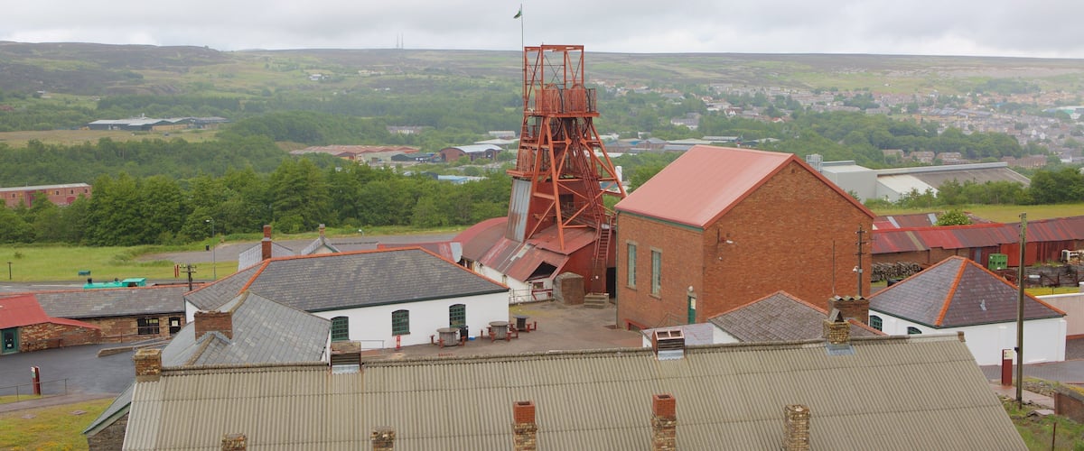 A mining complex with a prominent red tower, surrounded by industrial buildings and a rural landscape.