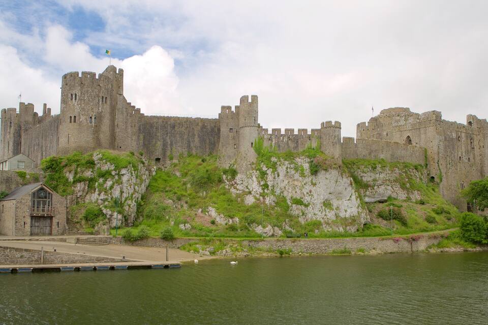 Un château historique doté d’un fossé et d’un petit bâtiment.
