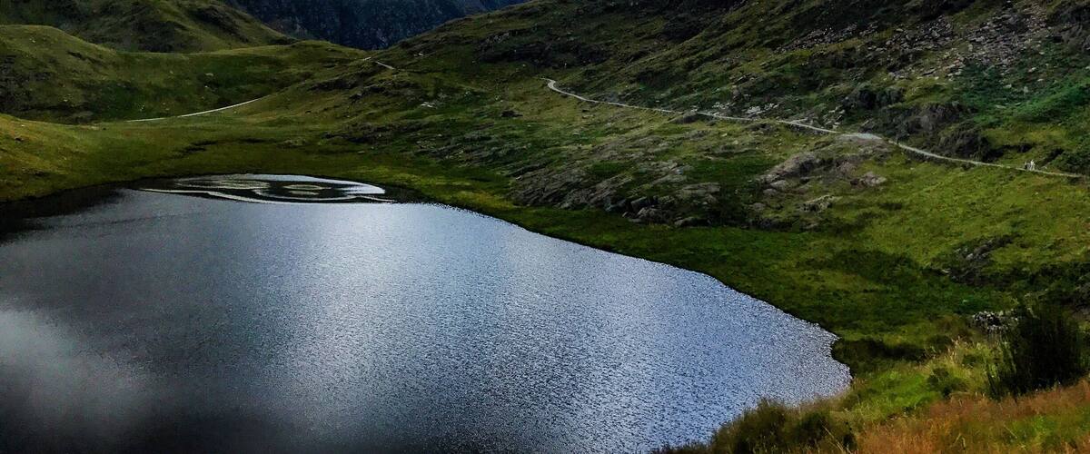 A lake surrounded by mountains with a winding road.