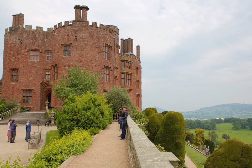 A historic castle with a large brick tower, a paved pathway, and well-manicured gardens.