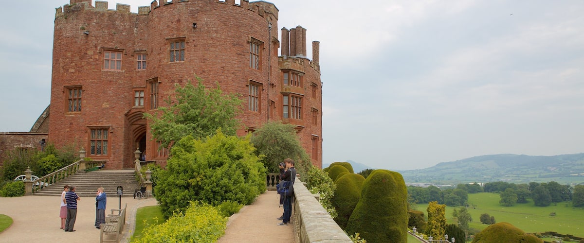A historic castle with a large brick tower, a paved pathway, and well-manicured gardens.