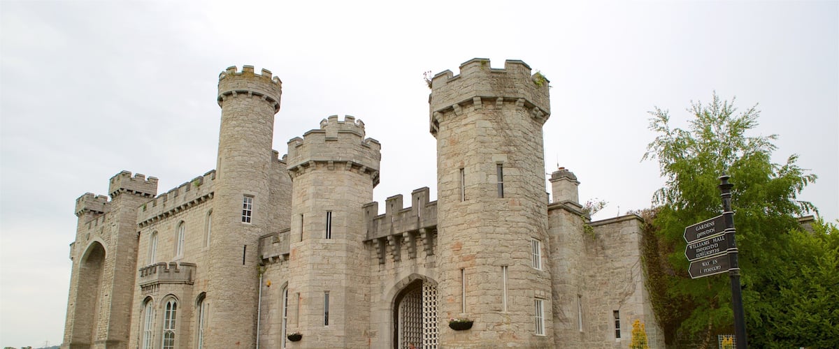 A large stone castle with multiple towers and a signpost indicating gardens, hall, and toilets.